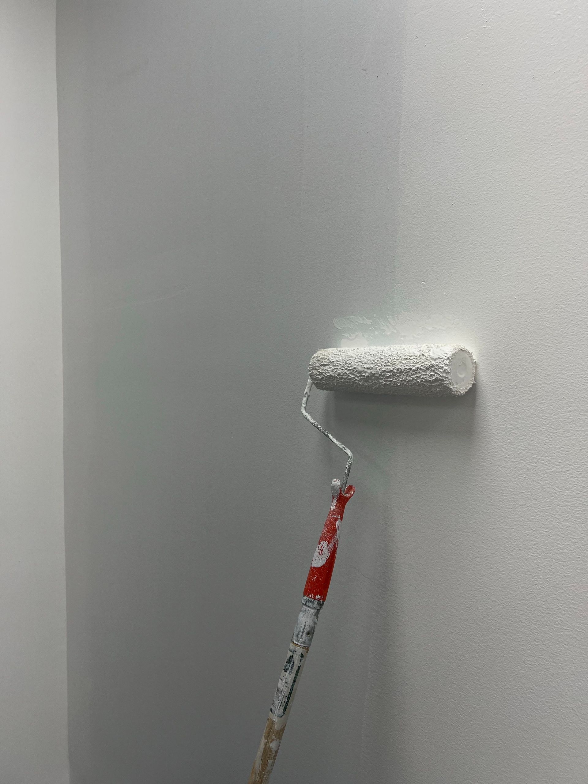 Smooth white paint applied on a wall using a roller, showcasing home renovation process.